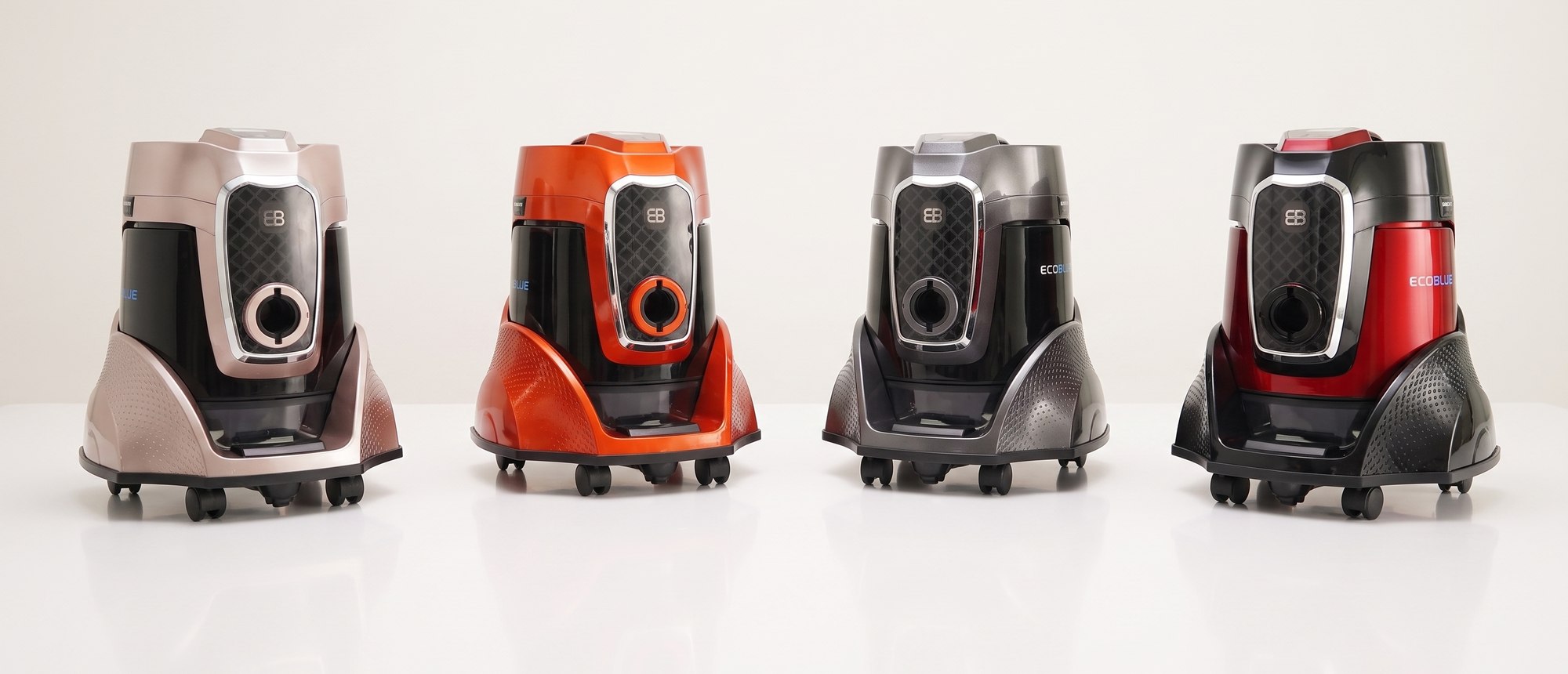 Four EcoBlue water-filtration vacuums side by side in rose gold, orange, graphite and red finishes